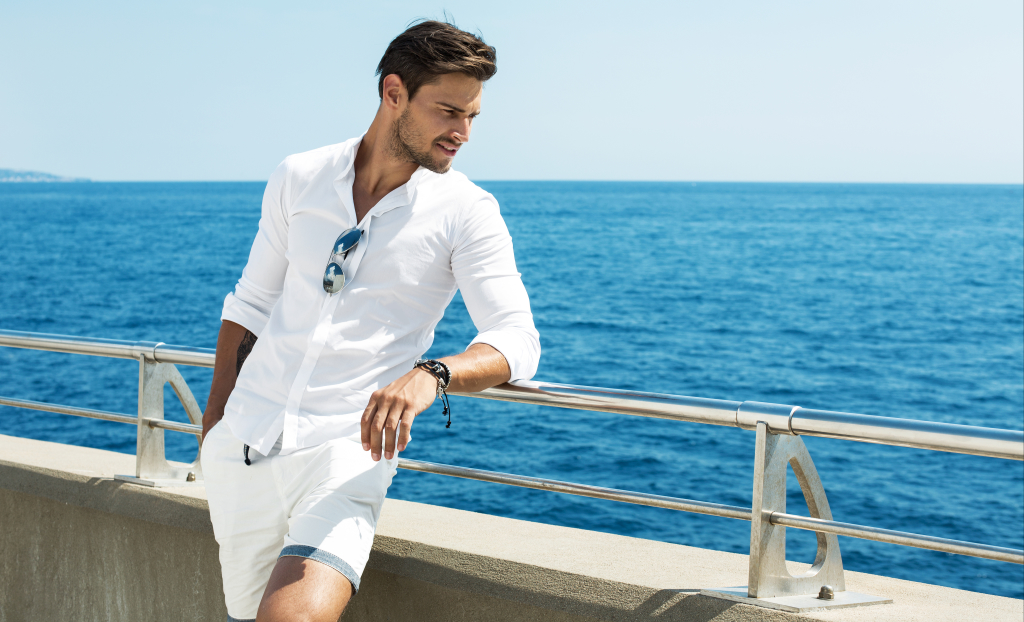 Handsome man wearing white clothes posing in sea scenery