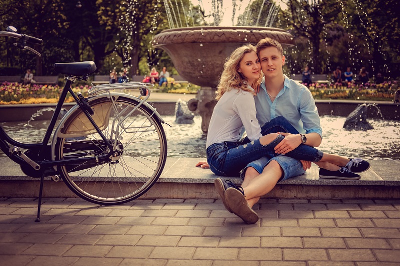 Cute urban couple posing near city fountain.