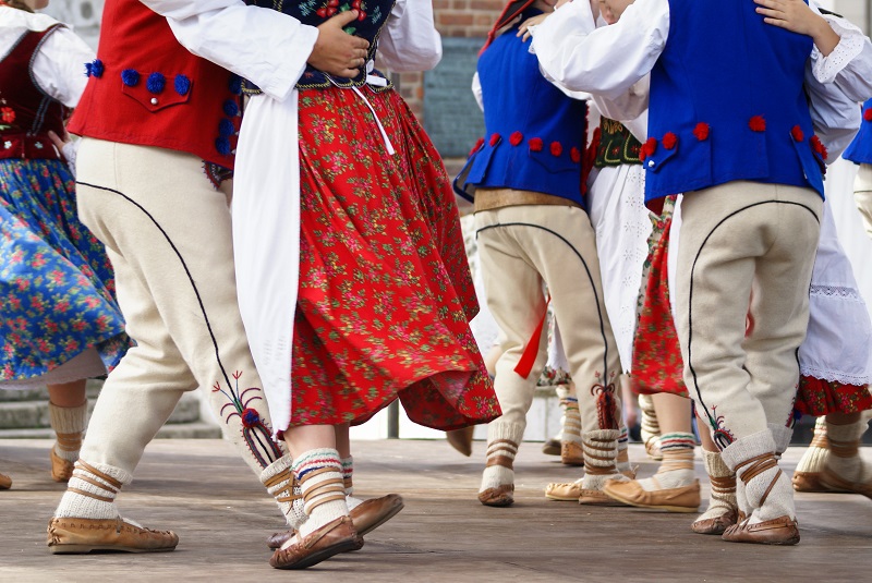 Horizontal colour image of female polish dancers in traditional folklore costumes on stage