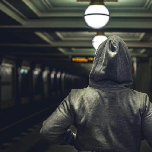 Person Wearing Gray Hooded Jacket in Train Station