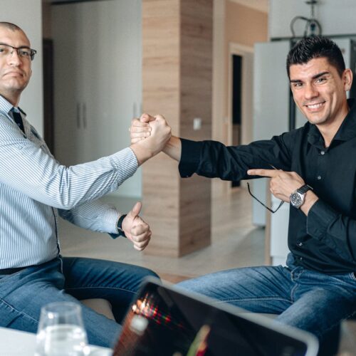 Two Men Sitting on Chairs Shaking Hands