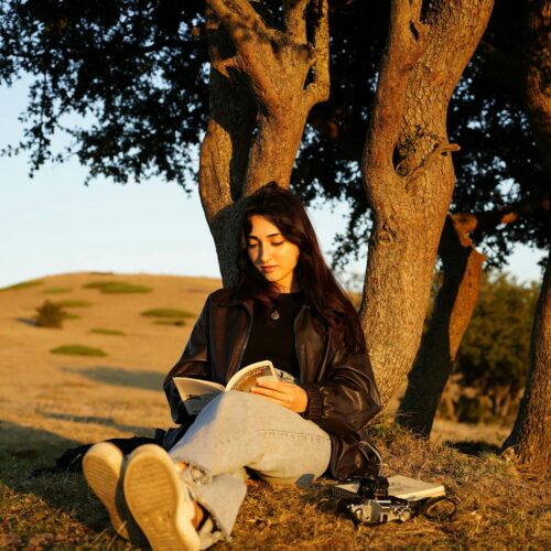 A woman sitting on the ground reading a book