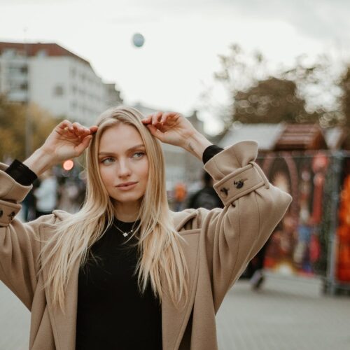 Young Woman in Coat Standing on the Sidewalk in City