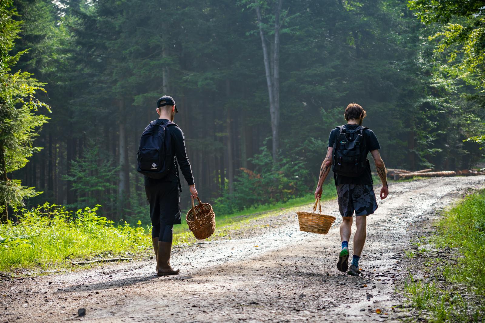 Two men walking down a dirt road with baskets